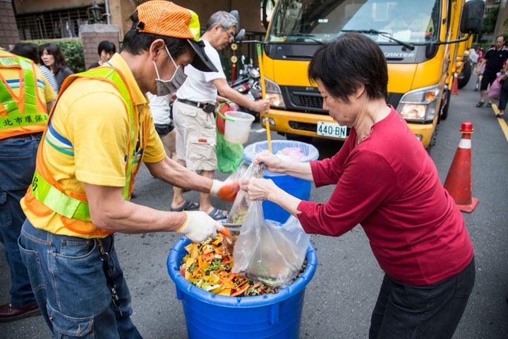 A city garbageman helps a resident dispose of food waste in Taipei.