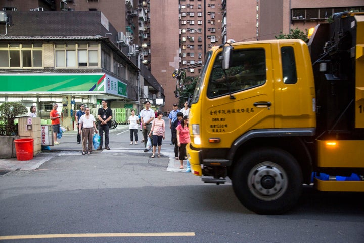 Taipei residents wait with their garbage for the trash collection trucks to arrive. Different trucks are used for garbage, recyclables and food waste.