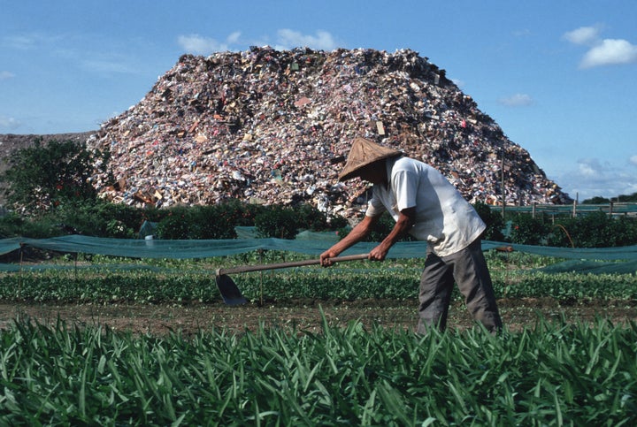 This 1991 photo shows a farmer whose field runs alongside a garbage dump just outside Taipei.