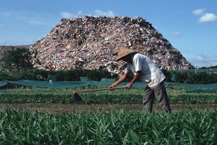 This 1991 photo shows a farmer whose field runs alongside a garbage dump just outside Taipei.