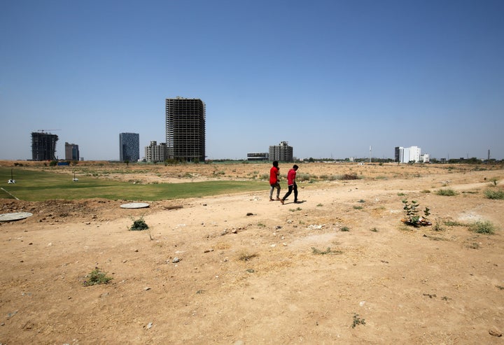 People walk past buildings under construction at the Gujarat International Finance Tec-City (GIFT) at Gandhinagar, Gujarat, March 18, 2019.