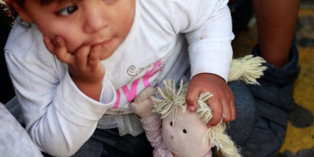 A member of a migrant family from Mexico, fleeing from violence, holds her doll while waiting to enter the United States to meet officers of the U.S. Customs and Border Protection on June 20.