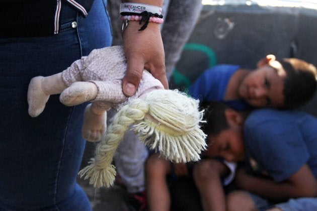 A Mexican woman holds a doll next to children at the Paso Del Norte Port of Entry, in the U.S.-Mexico border in Chihuahua state, Mexico on June 20.