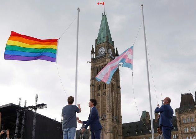Prime Minister Justin Trudeau, Ryan Brown, of Owen Sound, Ont., and MP Randy Boissonnault, right, raise the pride flag at a ceremony on Parliament Hill in Ottawa on June 20, 2018.