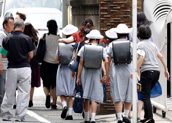 Elementary School students leave their school with parents following an attack in Kawasaki, near Tokyo.