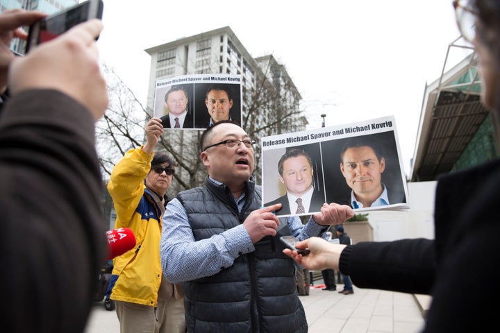 Louis Huang of Vancouver Freedom and Democracy for China holds photos of Canadians Michael Spavor and Michael Kovrig outside B.C. Supreme Court on Mar. 6, 2019