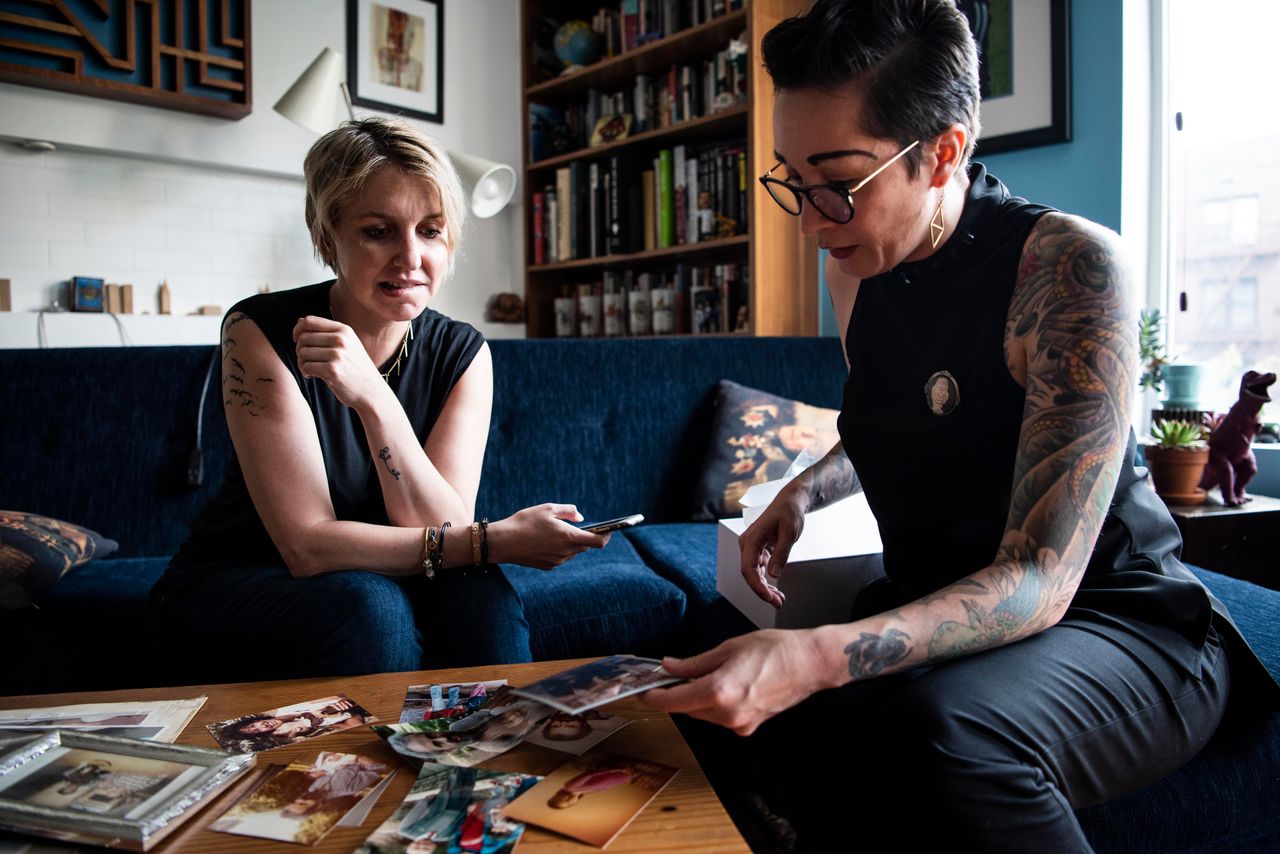 Jess McIntosh, left, and Ali Cole look over family pictures in Cole's Brooklyn, New York, home.