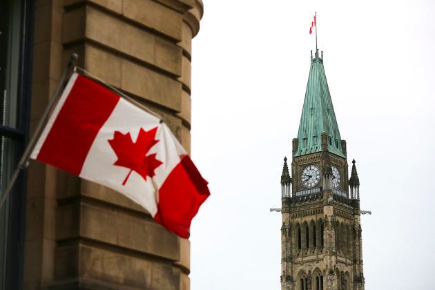 The Canadian Flag flies on a building in Ottawa across from the Peace Tower on Centre Block of Parliament Hill.