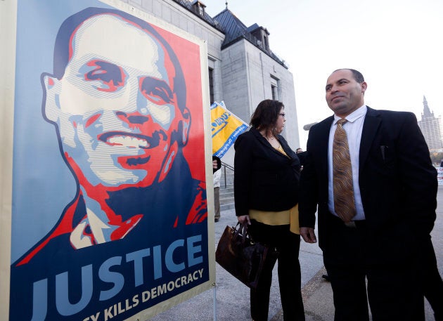 MMohamed Harkat looks at a sign held by supporters outside the Supreme Court of Canada in Ottawa on Oct. 10, 2013.