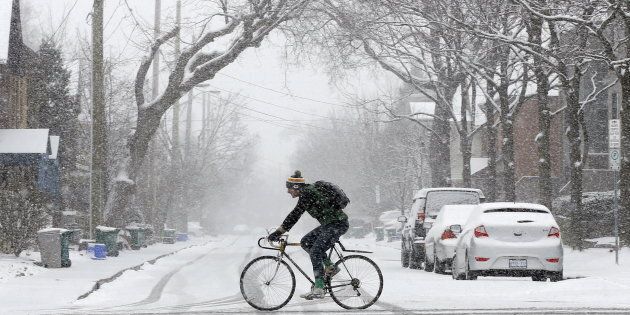A man rides a bicycle during a spring snow storm in Ottawa, April 6, 2016.