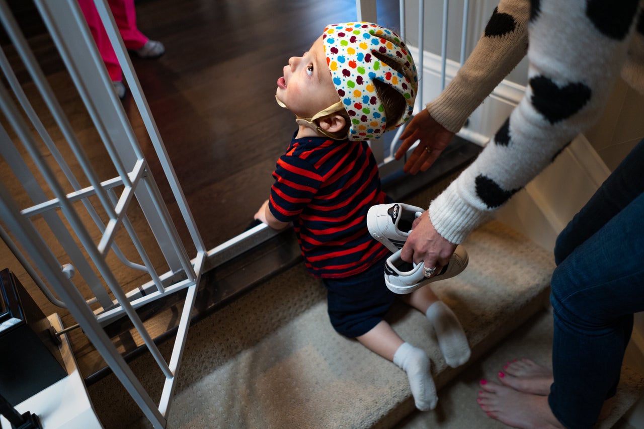 Maxwell Freed, who suffers from a rare genetic neurological disease, is helped to the top of a set of stairs at his home in Denver. Climbing the stairs is a new accomplishment for Maxwell, whose disease has delayed his physical and mental development.