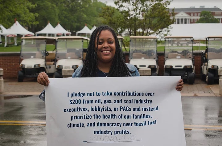 Mckayla Wilkes, 28, holds a sign bearing her signature on the No Fossil Fuel Money pledge. 