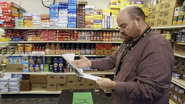 A high school principal looks over a supply list while standing in the school’s community food pantry in New London, Iowa. Food banks have been the beneficiaries of a U.S. Department of Agriculture program crafted to support farmers affected by the U.S. trade war with China. Leaders at food banks say the program has helped them provide their clients with healthy foods, although maintaining and distributing perishable goods has come with unexpected costs.