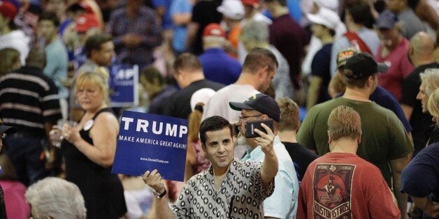 A supporter of Republican presidential candidate Donald Trump takes a picture while holding a sign before the start of a rally Friday, June 17, 2016, in The Woodlands, Texas. (AP Photo/David J. Phillip)