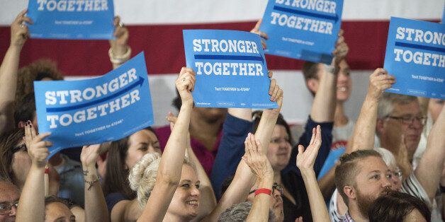 Attendees hold up signs as Hillary Clinton, former Secretary of State and presumptive Democratic presidential nominee, not pictured, speaks during a campaign event in Cincinnati, Ohio, U.S., on Monday, June 27, 2016. Clinton released a new national television ad on Sunday attacking likely Republican rival Donald Trump for his comments on the U.K's decision to leave the European Union, and later warned of the negative impact that 'bombastic' behavior can have at times of crisis. Photographer: Ty Wright/Bloomberg via Getty Images