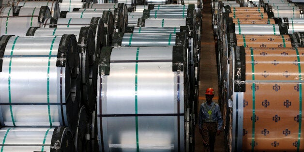 A worker walks past rolls of steel inside the China Steel Corporation factory, in Kaohsiung, southern Taiwan August 26, 2016. REUTERS/Tyrone Siu