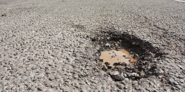 Large deep pothole an example of poor road maintance due to reducing local council repair budgets