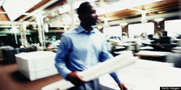 Man with rolled paper walking through office, blurred motion