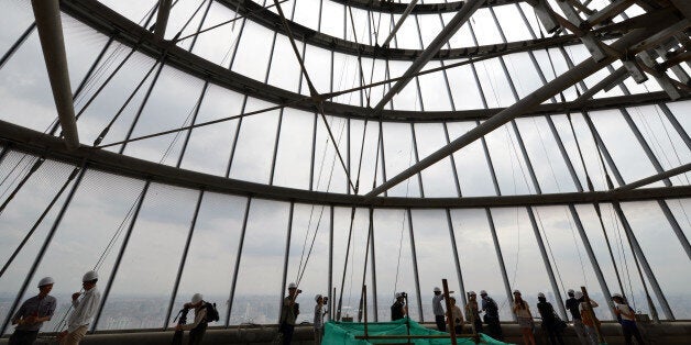 This photograph taken on August 2, 2013 shows journalists inside the under-construction Shanghai Tower in Shanghai. Work on the main structure of the world's second tallest skyscraper was completed on August 3 as a crane placed a steel beam 580 meters (1,900 feet) above the ground, as the building formally overtook Taiwan's 509 meter tall Taipei 101 building to become the tallest tower in Asia. AFP PHOTO/Peter PARKS (Photo credit should read PETER PARKS/AFP/Getty Images)