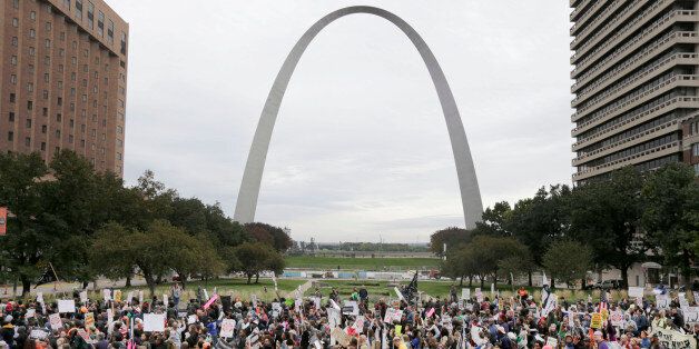 Protesters march past the St. Louis Arch, Saturday, Oct. 11, 2014, in St Louis. More than 1,000 gathered Saturday in downtown St. Louis for a second day of organized rallies to protest Michael Brownâs death and other fatal police shootings in the area and elsewhere. (AP Photo/Charles Rex Arbogast)