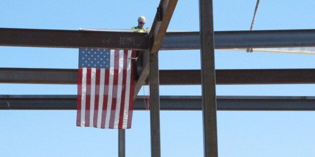 A worker installs the final, ceremonial steel beam atop the 18th floor of the Eighth and Main Tower on Wednesday, April 24, 2013, in Boise, Idaho. The installation of the last beam marks the halfway point in construction of the downtown building that will be the headquarters of Zion's Bank. (AP Photo/Todd Dvorak)