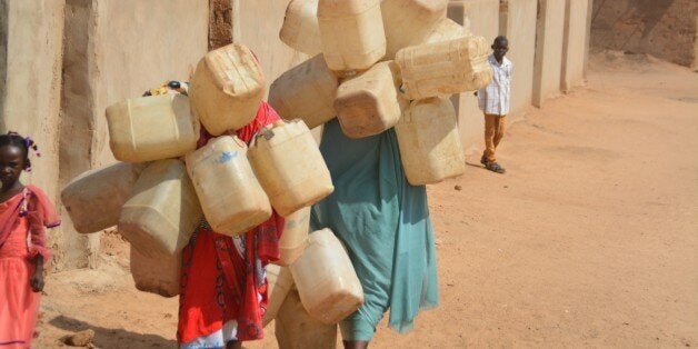 DARFUR, SUDAN - SEPTEMBER 26: Refugee woman carries plastic bottles to get water from a water-well as they try to live under