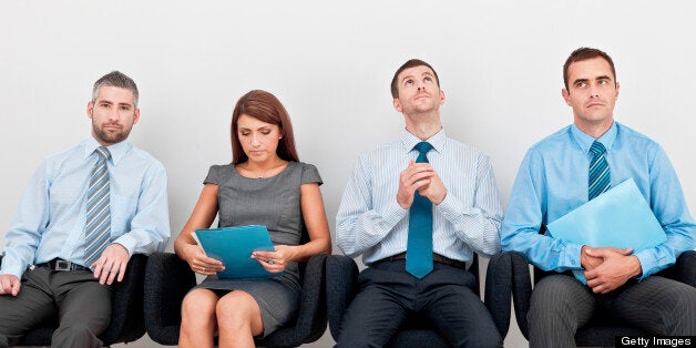 Four business people sitting on chairs in a row and waiting for an interview.