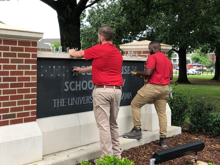 University of Alabama employees remove the name of Hugh F. Culverhouse Jr. off the School of Law sign in Tuscaloosa, Ala., Friday, June 7, 2019. 