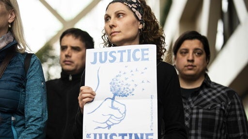 A woman holds a sign that reads "Justice for Justine."