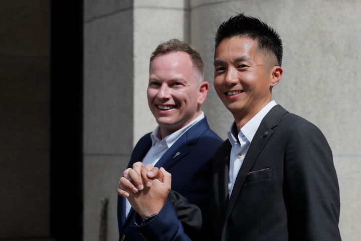 Angus Leung Chun-kwong, a senior immigration officer, right, and Scott Adams, a same-sex couple who married in New Zealand pose for photographers outside the Court of Final Appeal in Hong Kong. 