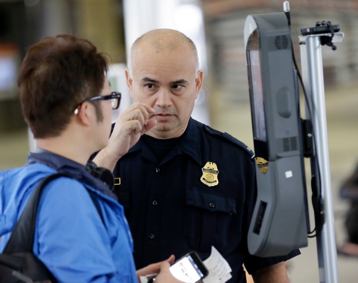 A U.S. Customs and Border Protection officer talks to a passenger at a face recognition kiosk at George Bush Intercontin