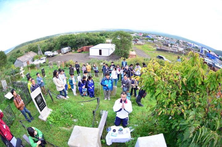 択捉島にある日本人墓地で手を合わせる日本人のビザなし訪問団＝2014年9月（魚眼レンズを使って撮影しています）