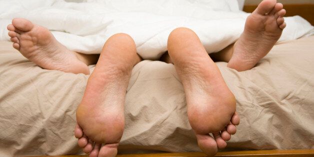 View of feet of couple having sex in bed.