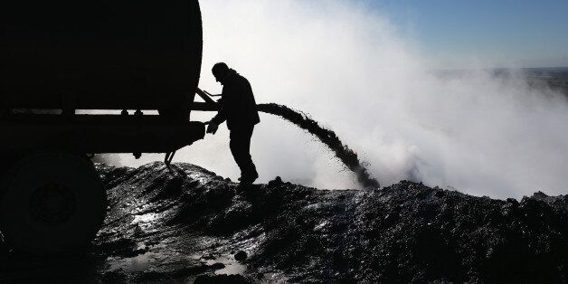 An worker unloads the dregs of oil refined into diesel fuel on November 14, 2015 near Derek, in Rojava, Syria.