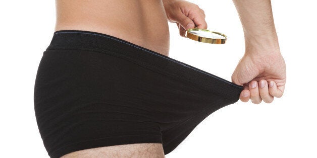 Man looking in his underwear with magnifying glass