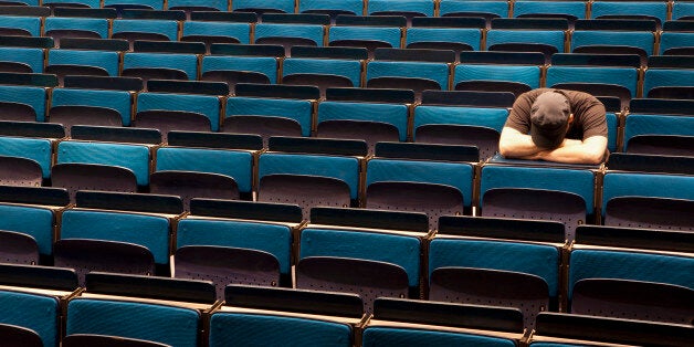 A man sitting in an auditorium with his head resting in his arms