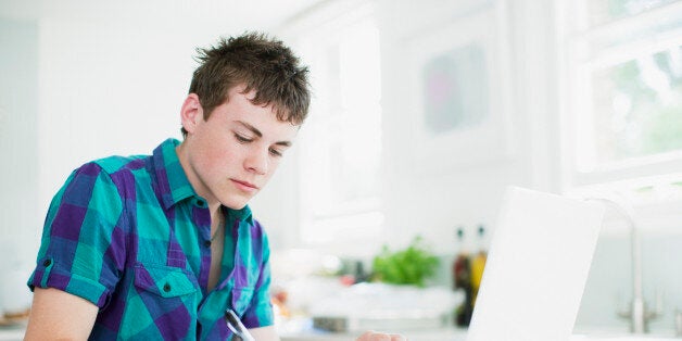 Teenage boy using laptop and doing homework