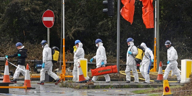 SHOREHAM, ENGLAND - AUGUST 24: Emergency service workers in protective overalls walk on the A27 road near where a Hawker Hunter fighter jet crashed during on August 24, 2015 in Shoreham, England. The aircraft came down while performing at the Shoreham Airshow on August 22nd. Police now expect the death toll to rise to as many as 20 victims. (Photo by Peter Macdiarmid/Getty Images)