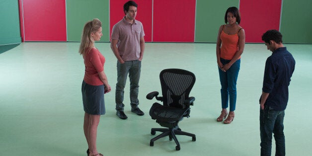 Business people standing around empty chair