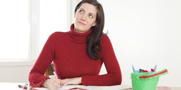 Young woman thinking and signing holiday cards