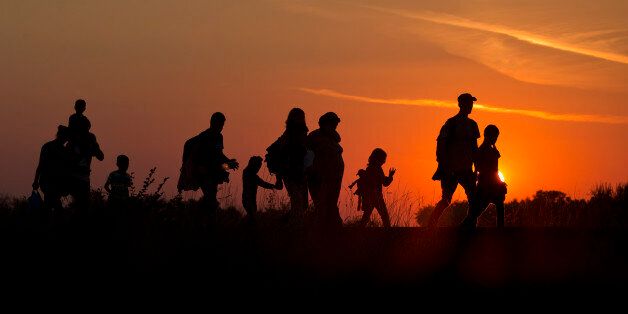 Refugees from the Middle East are silhouetted against the setting sun as they walk on railway tracks from Serbia, in Roszke, Hungary, Sunday, Aug. 30, 2015. Migrants fearful of death at sea in overcrowded and flimsy boats have increasingly turned to using a land route to Europe through the Western Balkans. (AP Photo/Darko Bandic)