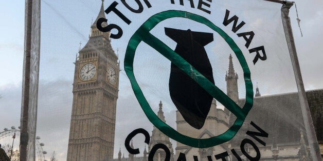 LONDON, ENGLAND - DECEMBER 02: Stop the War Coalition supporters hold up a banner outside the Houses of Parliament on December 2, 2015 in London, England. A day long debate on whether Britain should become involved with airstrikes targetting Islamic State targets in Syria will end in a vote at 10pm tonight. (Photo by Chris Ratcliffe/Getty Images)