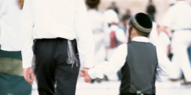 Israel, Jerusalem, two Orthodox Jewish boys wearing kippas and holding hands, rear view