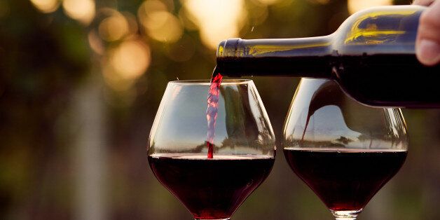 Pouring red wine into glasses in the vineyard, toned