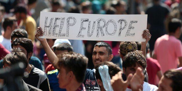 A man hold a placard reading 'Help Europe' as Syrian and Afgan refugees attend a protest rally to demand to travel to Germany on September 2, 2015 outside the Keleti (East) railway station in Budapest. Hungarian authorities face mounting anger from thousands of migrants who are unable to board trains to western European countries after the main Budapest station was closed. AFP PHOTO / FERENC ISZA (Photo credit should read FERENC ISZA/AFP/Getty Images)
