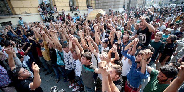 Syrian and Afgan refugees shout slogans during a protest rally to demand to travel to Germany on September 2, 2015 outside the Keleti (East) railway station in Budapest. Hungarian authorities face mounting anger from thousands of migrants who are unable to board trains to western European countries after the main Budapest station was closed. AFP PHOTO / FERENC ISZA (Photo credit should read FERENC ISZA/AFP/Getty Images)