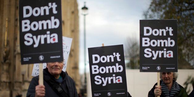 Supporters of the Stop the War Coalition hold placards protesting against Britain launching airstrikes against Islamic State extremists inside Syria, outside the Houses of Parliament as a debate goes on before a vote, Wednesday, Dec. 2, 2015. The vote expected Wednesday evening would authorize bombing inside Syria. Britain has been participating in U.S.-led coalition attacks against IS positions in Iraq only. (AP Photo/Matt Dunham)
