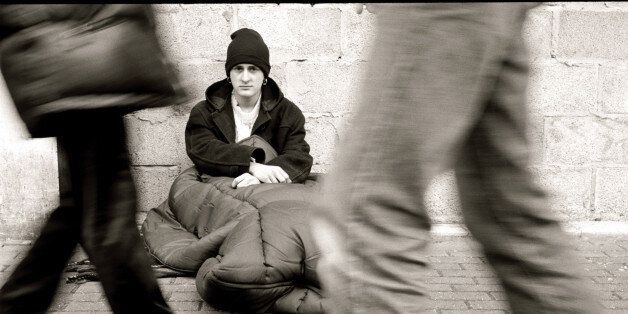 People walking by homless man, sitting on street, (B&W)