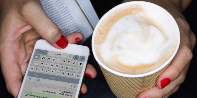 Female holding take away coffee, texting, close up