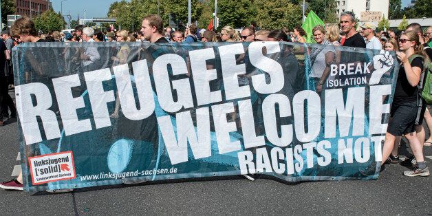 Protesters demonstrate with a banner 'Refugees welcome!' in Dresden, eastern Germany, Saturday, Aug. 29, 2015. A refugee shelter was attacked by far-right protesters in Heidenau near Dresden over the last weekend. (AP Photo/Jens Meyer)